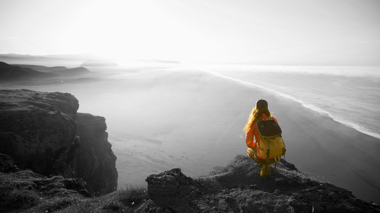 A Hiker with backpack squatting on top of a mountain and enjoying the view; image used for HSBC Every Global Account.